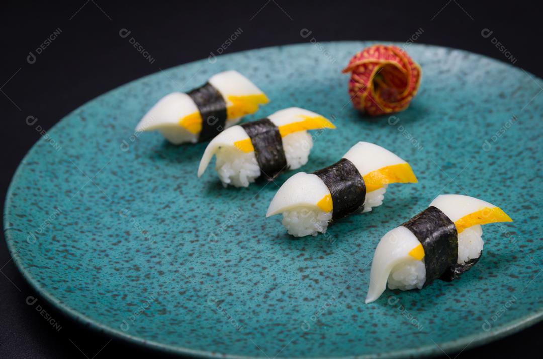 Sushi, cozinha tradicional japonesa. Delicioso sushi Hadock Tako na placa decorada, fundo preto.