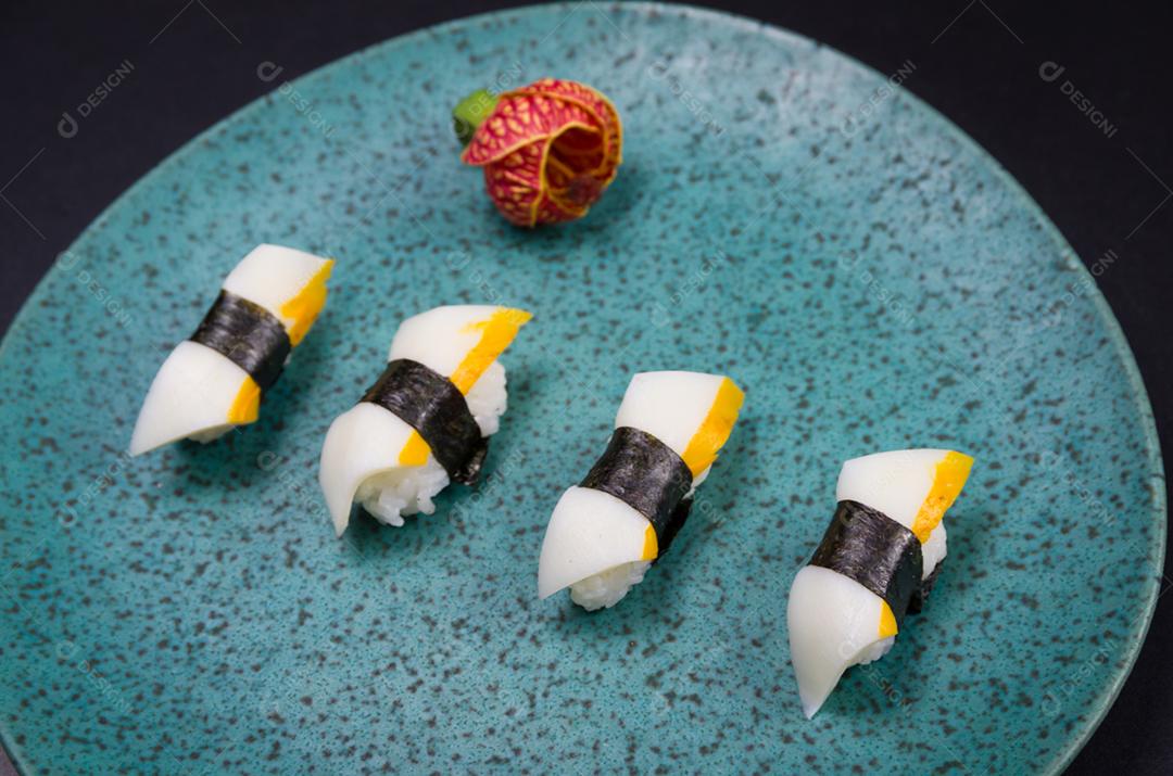 Sushi, cozinha tradicional japonesa. Delicioso sushi Hadock Tako na placa decorada, fundo preto.