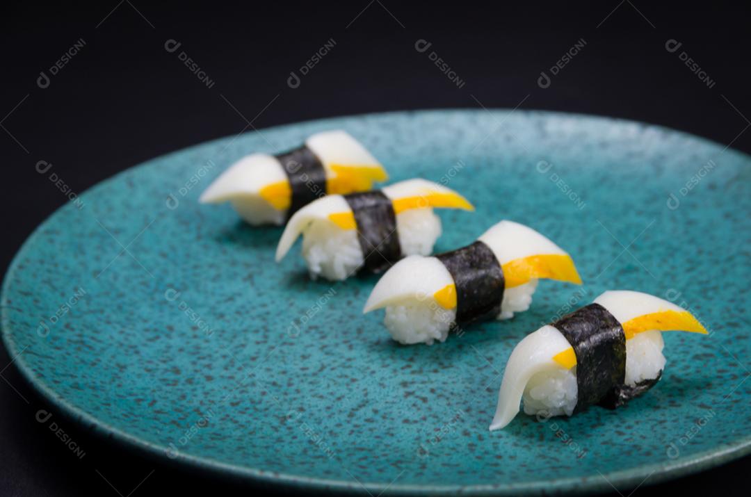 Sushi, cozinha tradicional japonesa. Delicioso sushi Hadock Tako na placa decorada, fundo preto.