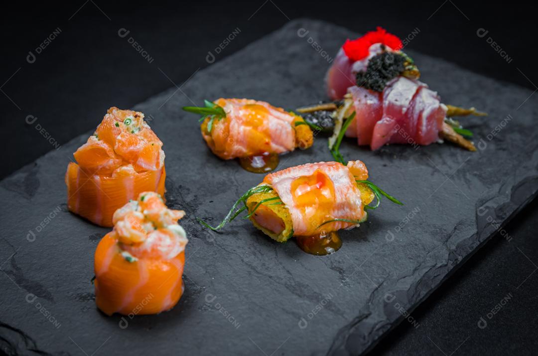 Sushi, cozinha tradicional japonesa. Vários deliciosos sushis no prato decorado, fundo preto