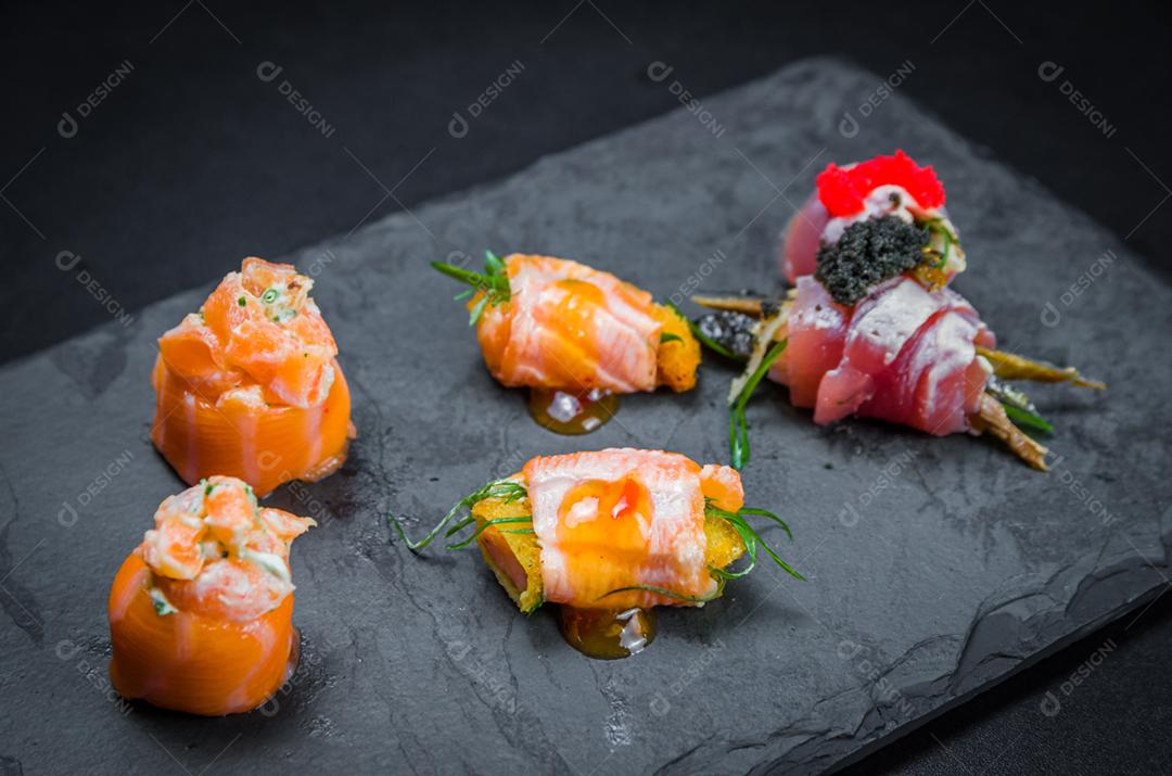 Sushi, cozinha tradicional japonesa. Vários deliciosos sushis no prato decorado, fundo preto