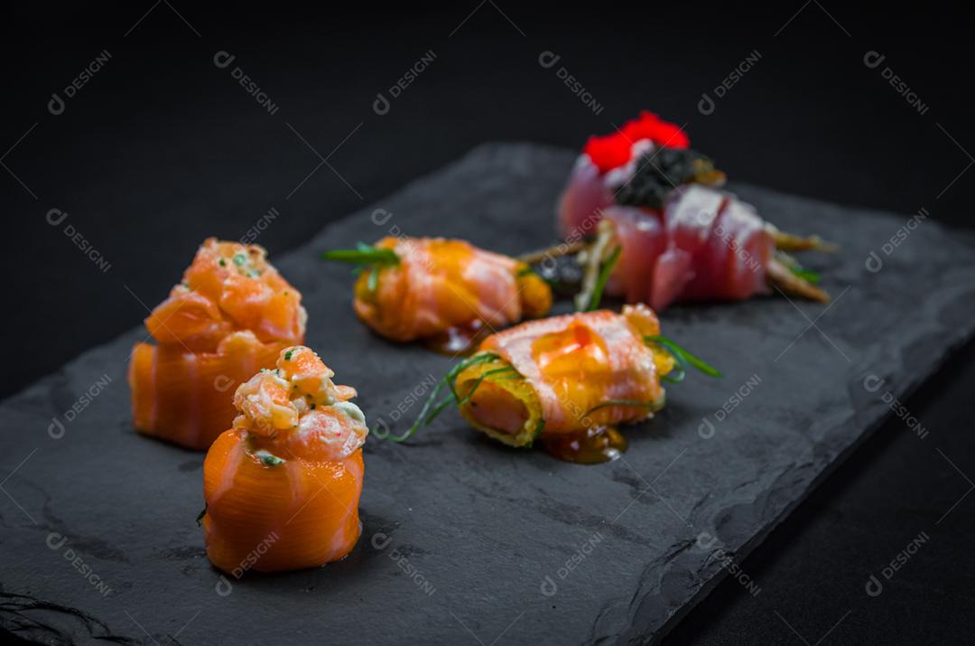 Sushi, cozinha tradicional japonesa. Vários deliciosos sushis no prato decorado, fundo preto