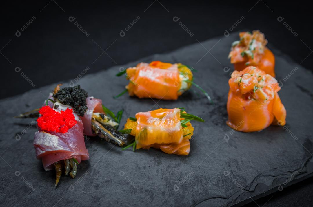 Sushi, cozinha tradicional japonesa. Vários deliciosos sushis no prato decorado, fundo preto