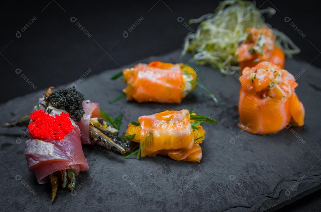 Sushi, cozinha tradicional japonesa. Vários deliciosos sushis no prato decorado, fundo preto
