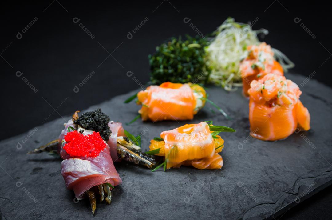 Sushi, cozinha tradicional japonesa. Vários deliciosos sushis no prato decorado, fundo preto