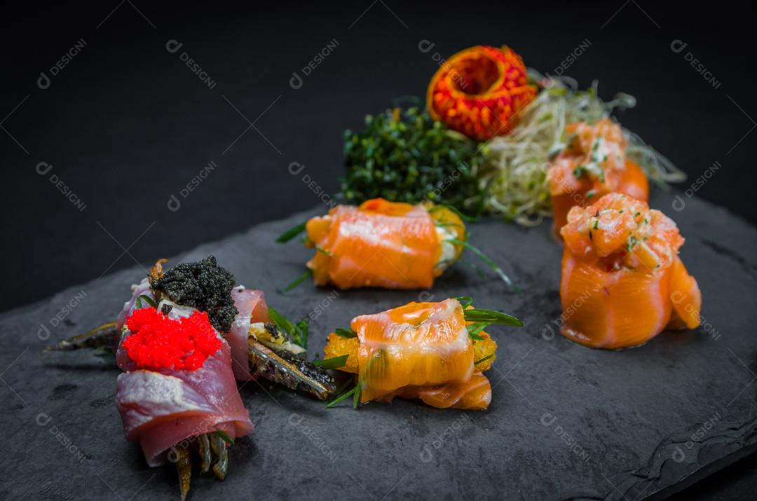 Sushi, cozinha tradicional japonesa. Vários deliciosos sushis no prato decorado, fundo preto