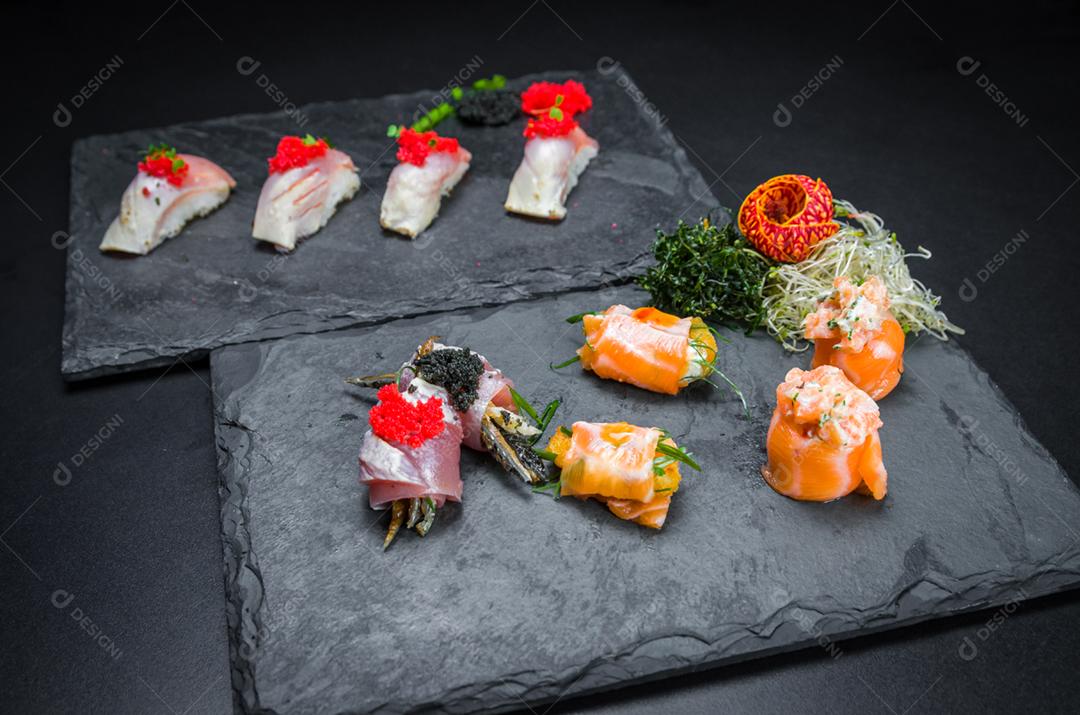 Sushi, cozinha tradicional japonesa. Vários deliciosos sushis no prato decorado, fundo preto