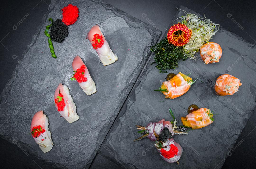 Sushi, cozinha tradicional japonesa. Vários deliciosos sushis no prato decorado, fundo preto