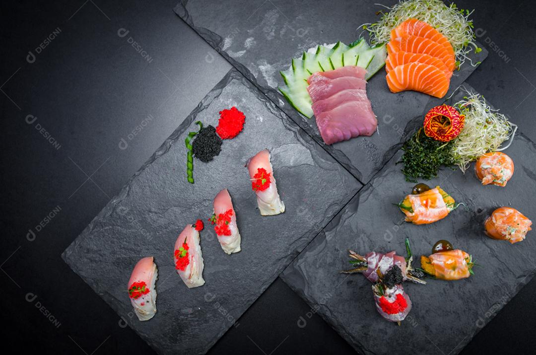 Sushi, cozinha tradicional japonesa. Vários deliciosos sushis no prato decorado, fundo preto