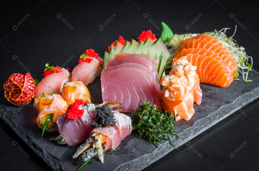 Sushi, cozinha tradicional japonesa. Vários deliciosos sushis no prato decorado, fundo preto