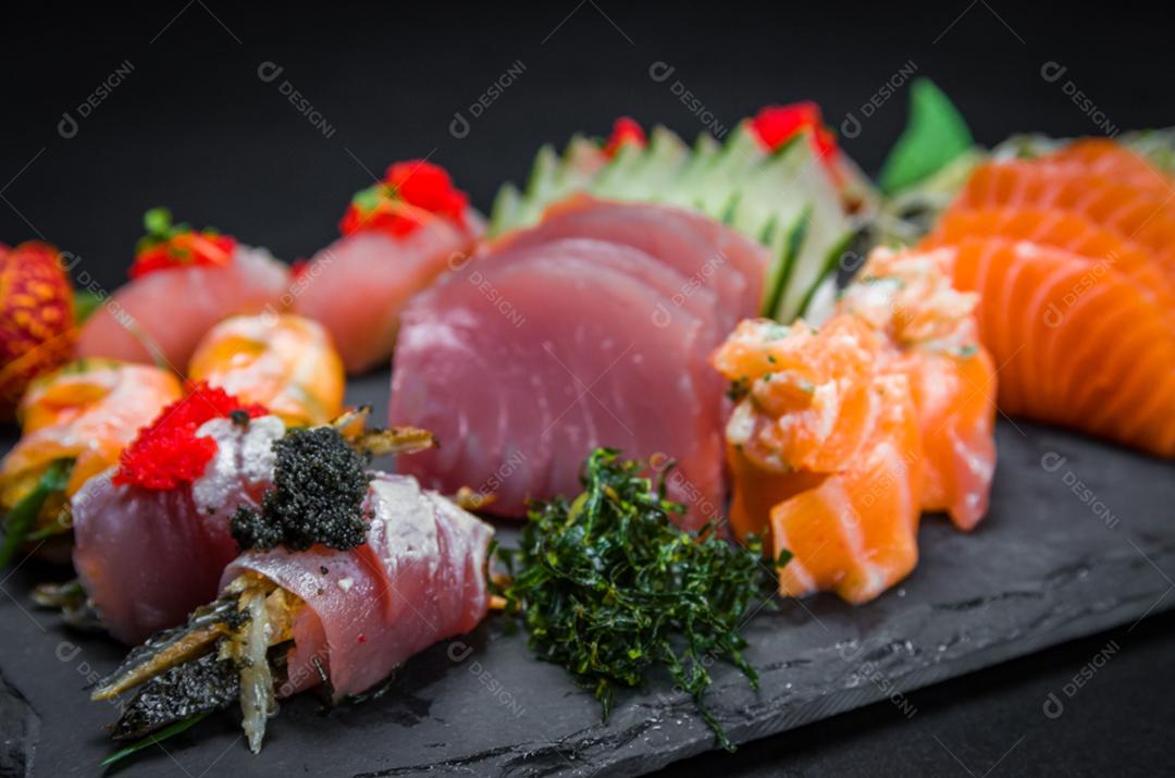 Sushi, cozinha tradicional japonesa. Vários deliciosos sushis no prato decorado, fundo preto
