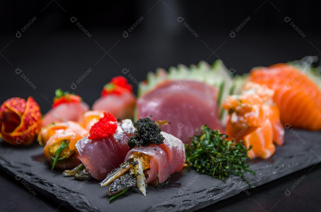 Sushi, cozinha tradicional japonesa. Vários deliciosos sushis no prato decorado, fundo preto