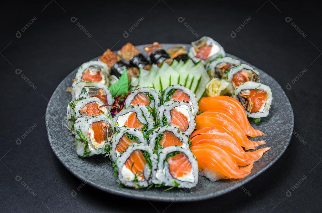 Sushi, cozinha tradicional japonesa. Vários deliciosos sushis no prato decorado, fundo preto