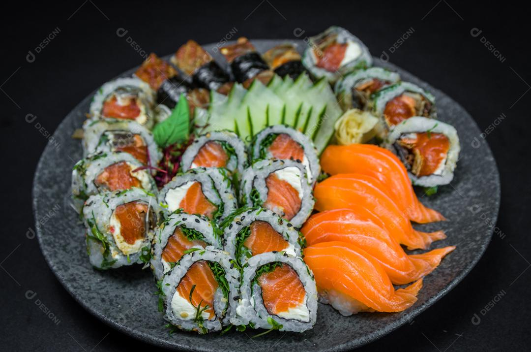 Sushi, cozinha tradicional japonesa. Vários deliciosos sushis no prato decorado, fundo preto