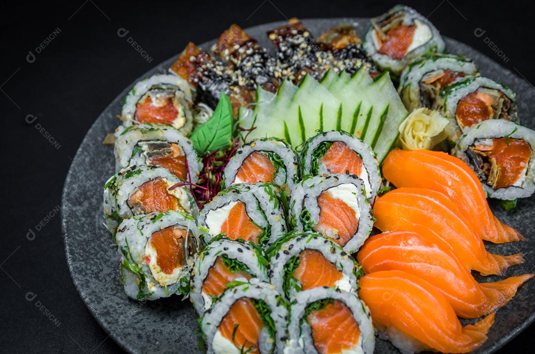 Sushi, cozinha tradicional japonesa. Vários deliciosos sushis no prato decorado, fundo preto