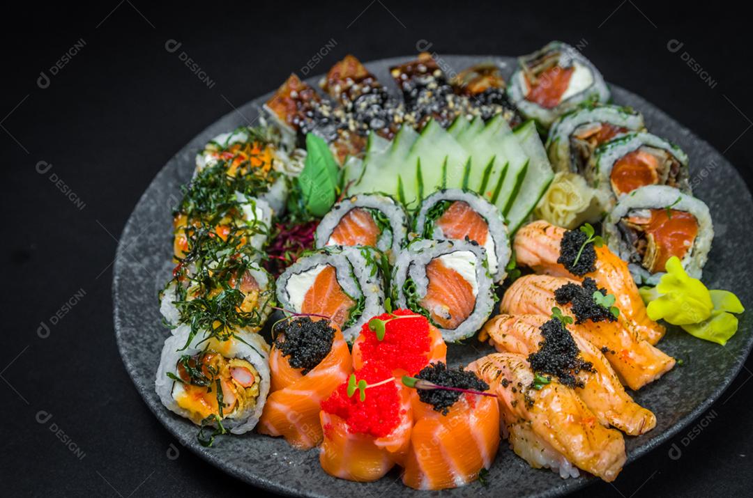 Sushi, cozinha tradicional japonesa. Vários deliciosos sushis no prato decorado, fundo preto