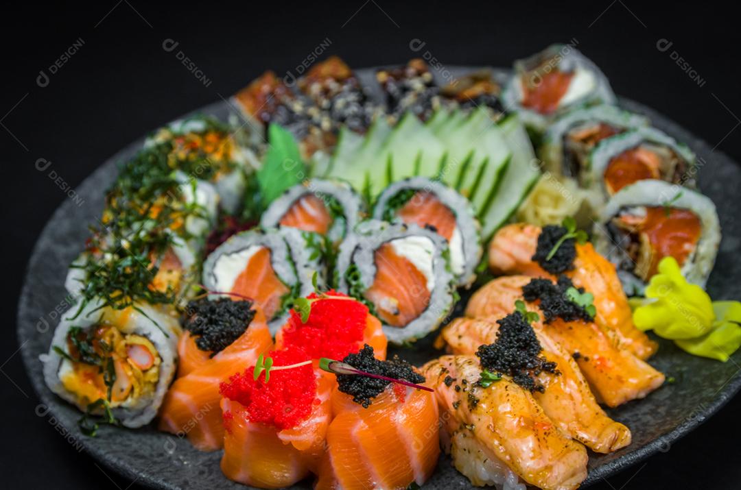Sushi, cozinha tradicional japonesa. Vários deliciosos sushis no prato decorado, fundo preto