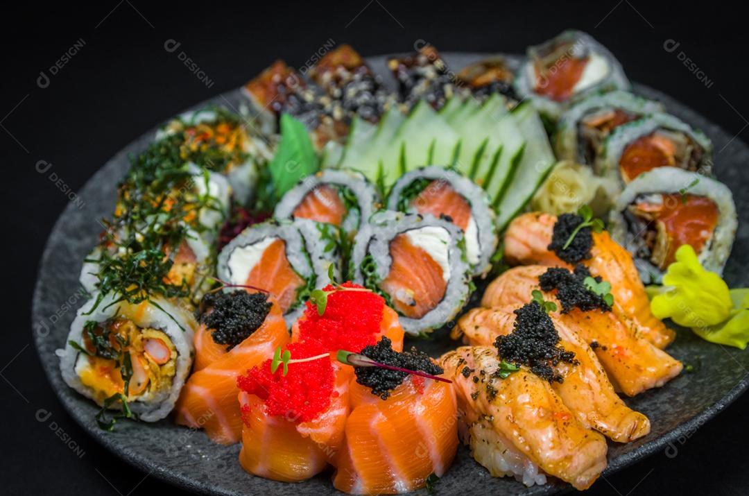 Sushi, cozinha tradicional japonesa. Vários deliciosos sushis no prato decorado, fundo preto