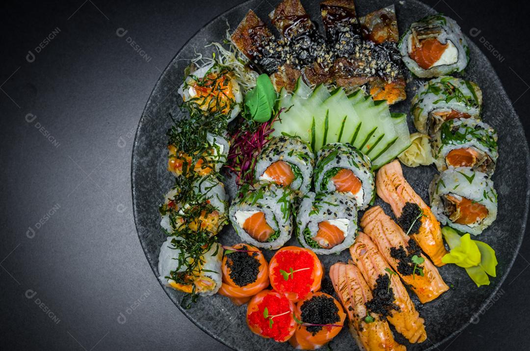 Sushi, cozinha tradicional japonesa. Vários deliciosos sushis no prato decorado, fundo preto