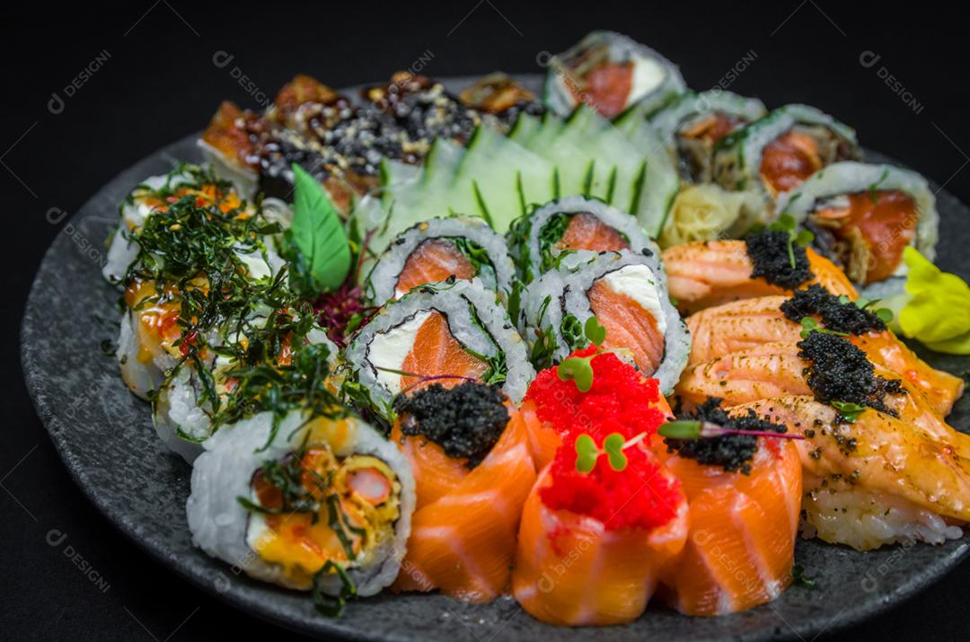 Sushi, cozinha tradicional japonesa. Vários deliciosos sushis no prato decorado, fundo preto