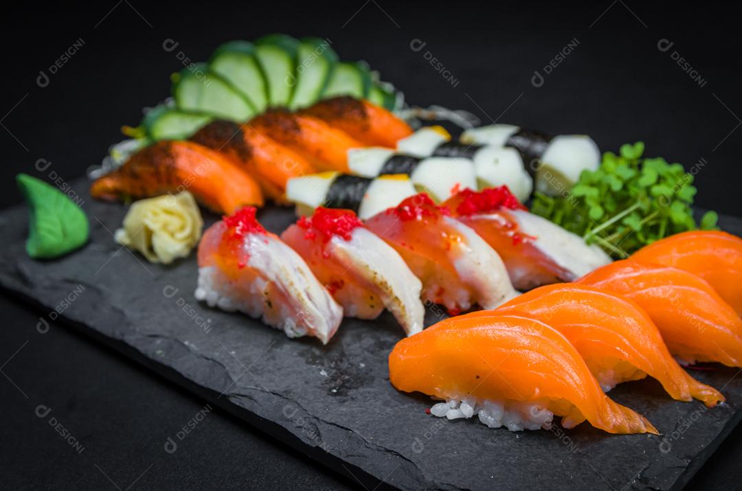Sushi, cozinha tradicional japonesa. Vários deliciosos sushis no prato decorado, fundo preto