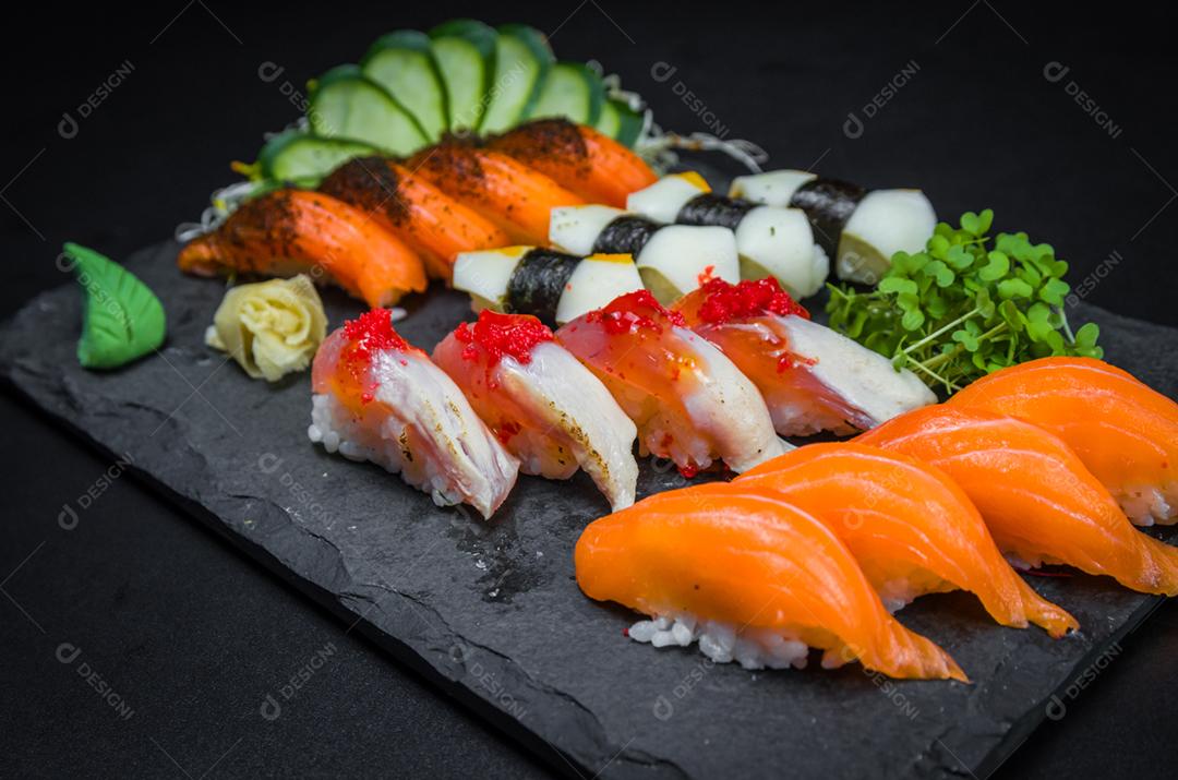 Sushi, cozinha tradicional japonesa. Vários deliciosos sushis no prato decorado, fundo preto