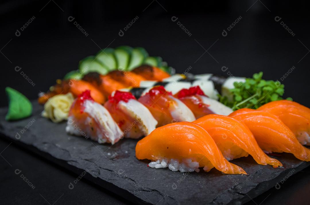Sushi, cozinha tradicional japonesa. Vários deliciosos sushis no prato decorado, fundo preto