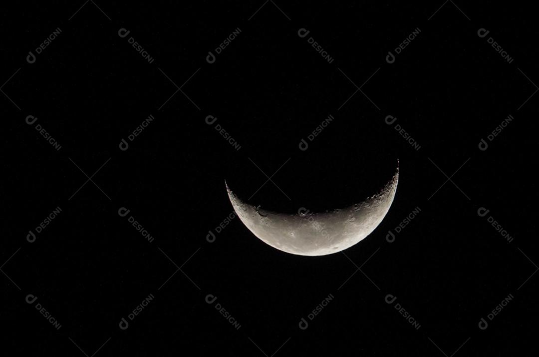 Linda foto da lua minguante em com céu escuro ao fundo.