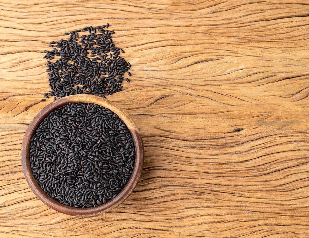 Raw black rice in bowl on wooden table