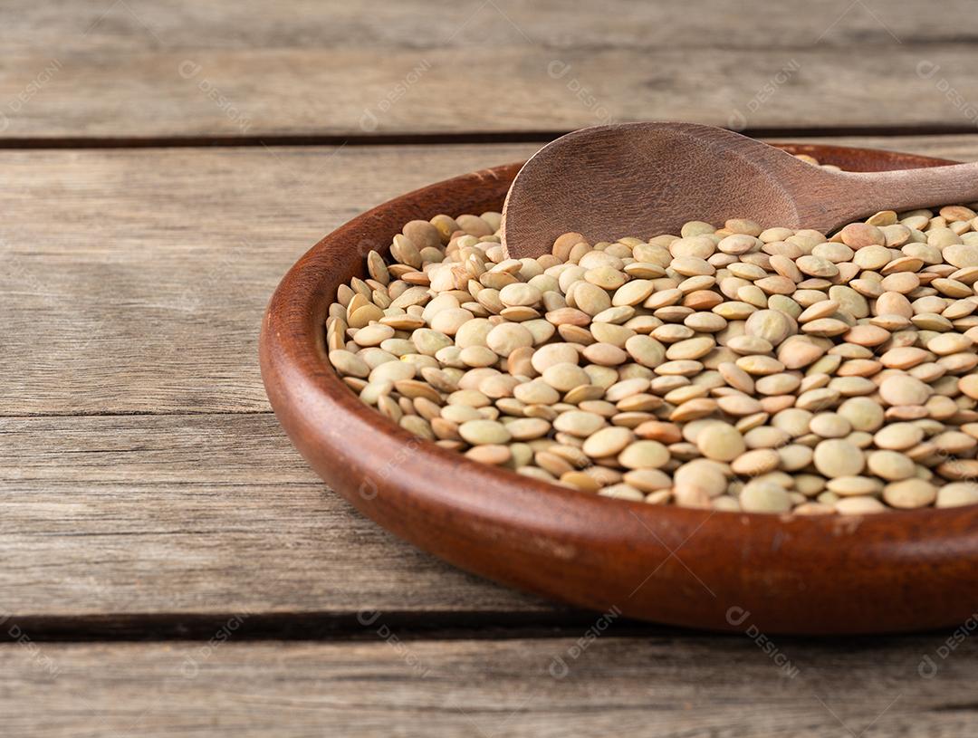 Lentilhas cruas em um prato sobre a mesa de madeira com curta profundidade de campo.