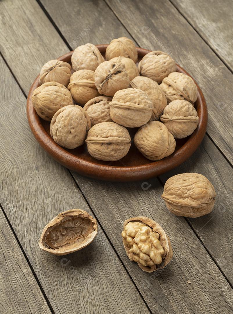 Nozes sobre uma mesa de madeira e em um prato.