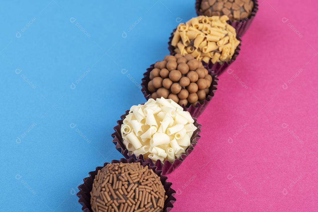 Brigadeiros típicos brasileiros, vários sabores sobre fundo colorido com espaço para texto.