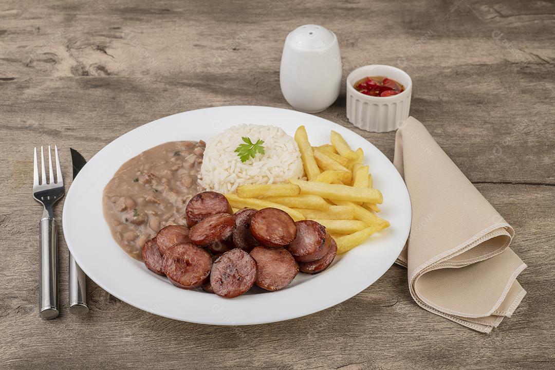 Salsicha, arroz, feijão e batata frita. Prato executivo típico do Brasil.