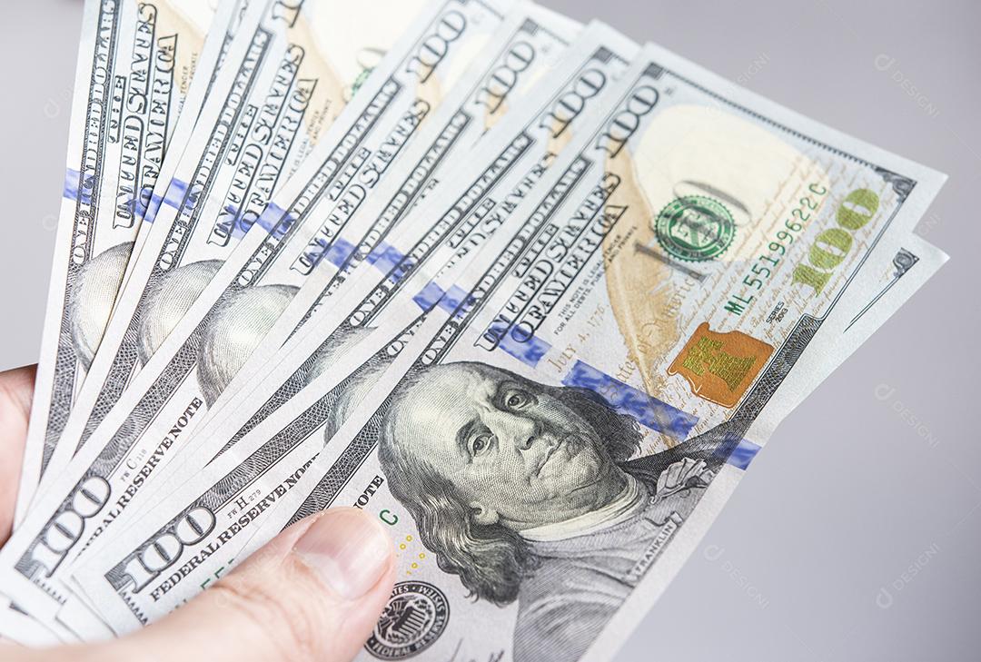 Mão segurando notas de cem dólares