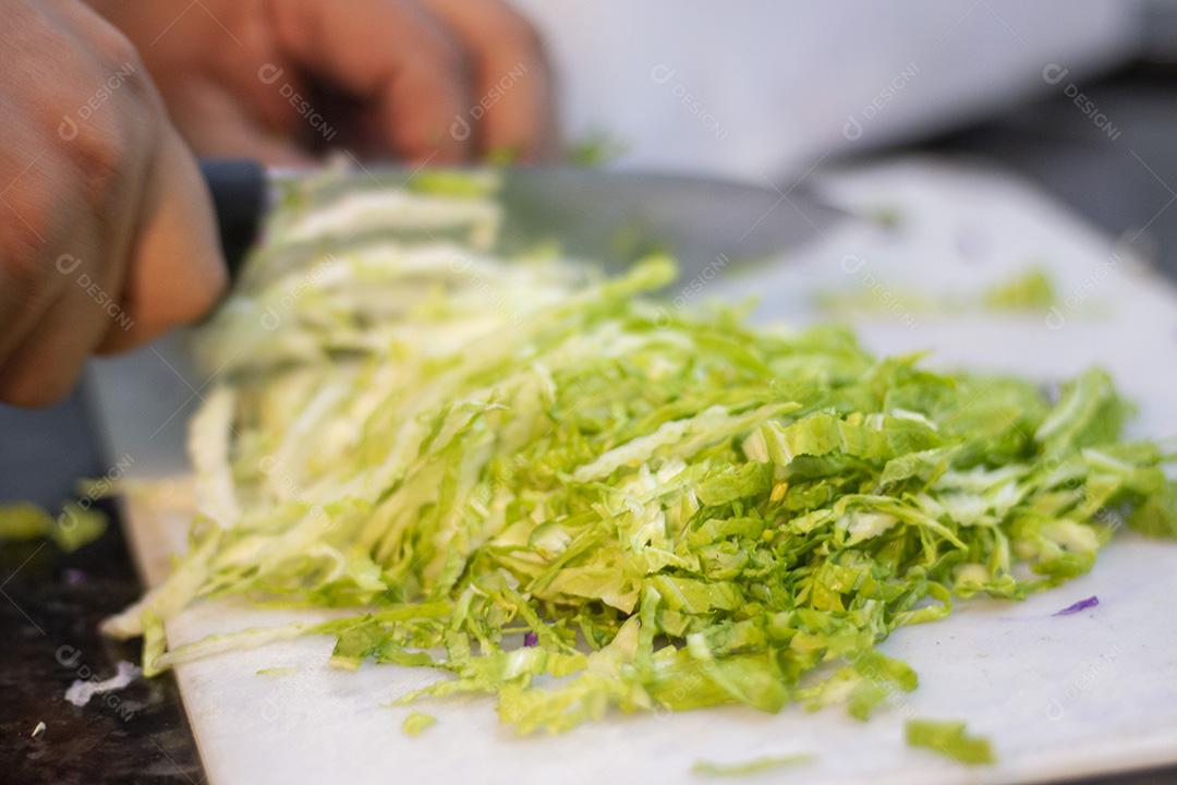 Cortando repolho para salada sobre placa branca.