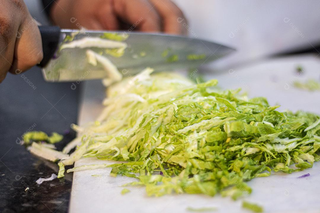 Cortando repolho para salada sobre placa branca.