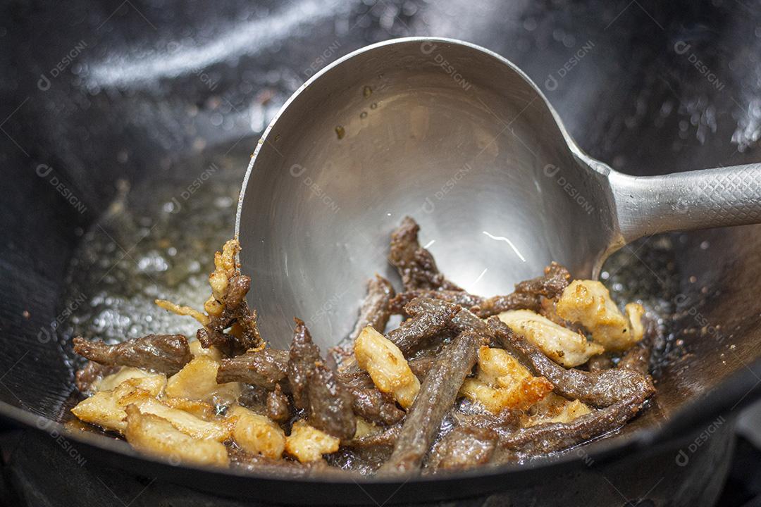 Fritando carne e frango em óleo fervente.