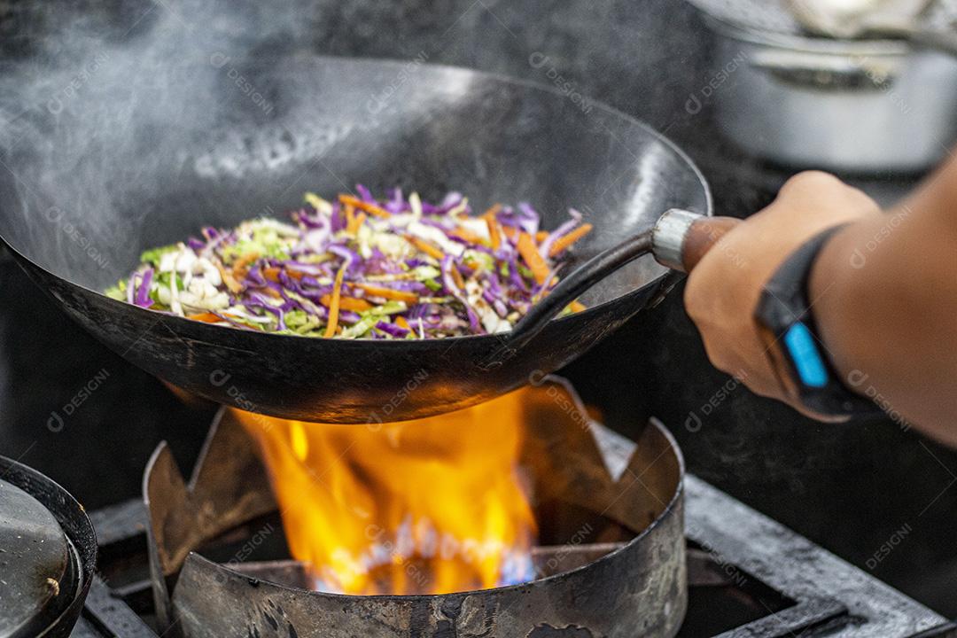 Salada frita sobre panela com óleo fervendo