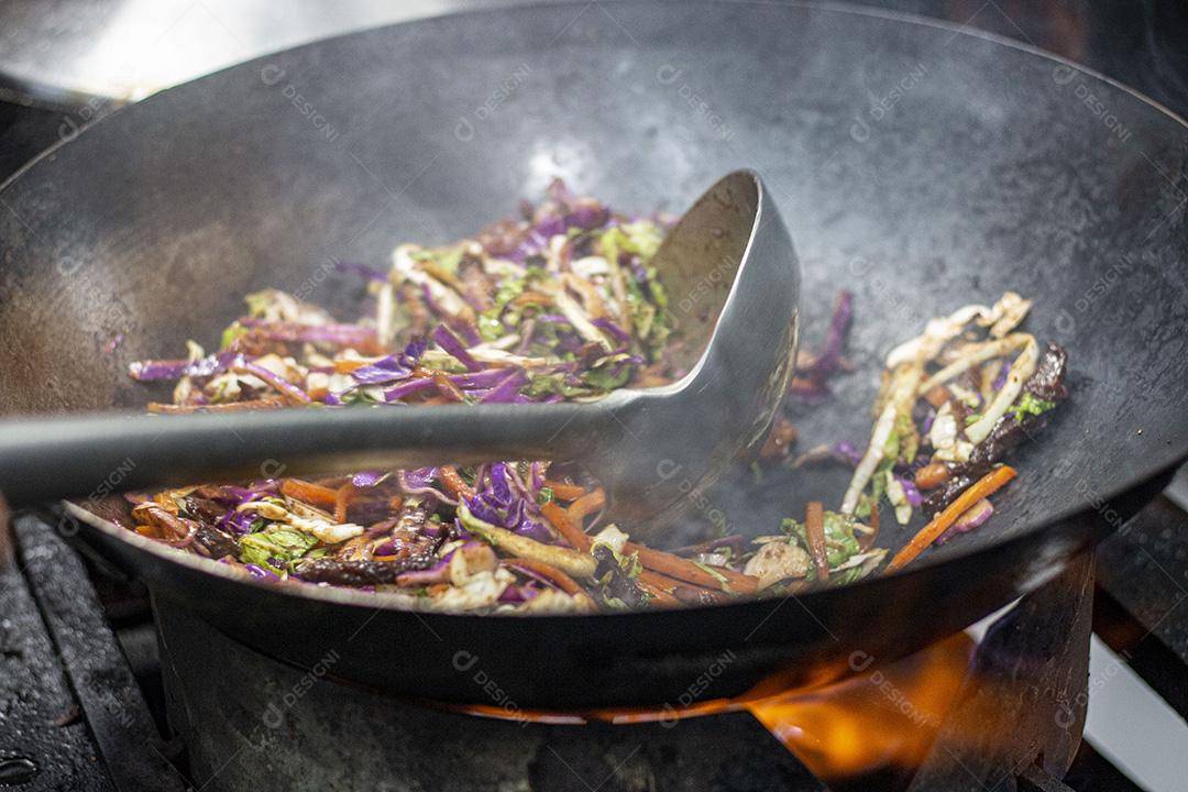 Salada colorida frita sobre panela com óleo fervendo