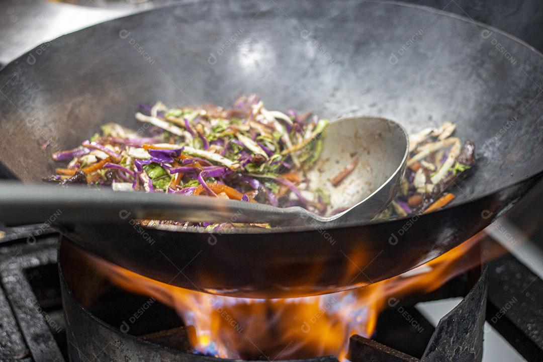 Salada colorida frita sobre panela com óleo fervendo