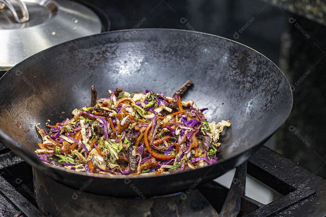 Salada colorida frita sobre panela com óleo fervendo