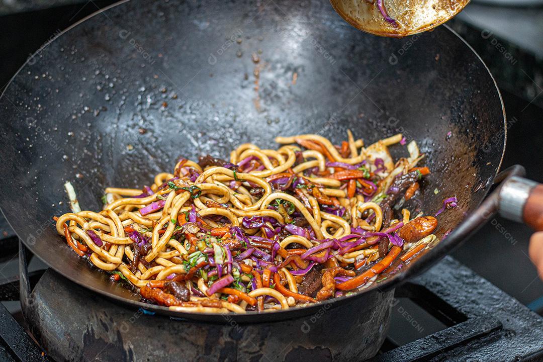 Salada colorida frita sobre panela com óleo fervendo