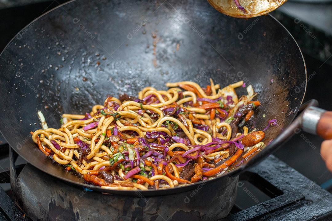 Salada colorida frita sobre panela com óleo fervendo