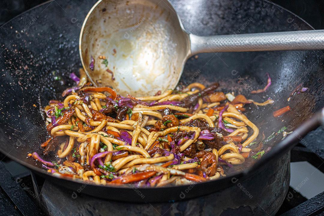 Salada colorida frita sobre panela com óleo fervendo