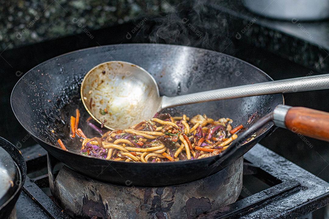 Salada colorida frita sobre panela com óleo fervendo