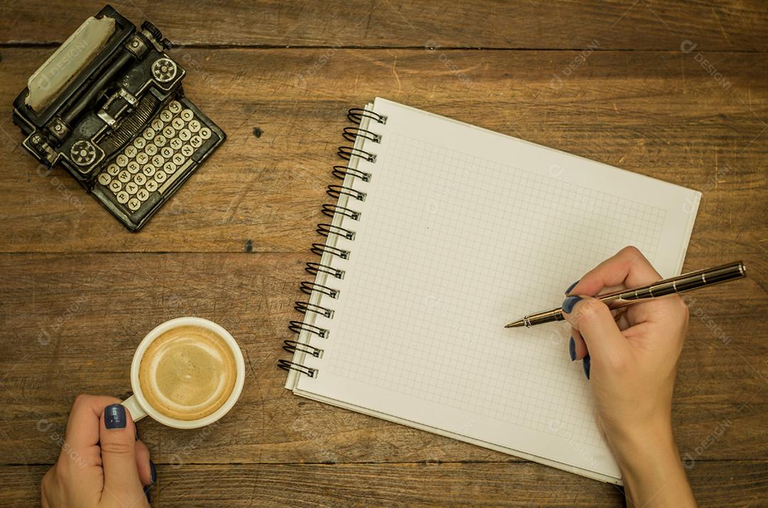 Jovem bebendo café sobre uma xicara de cafe caderno caneta