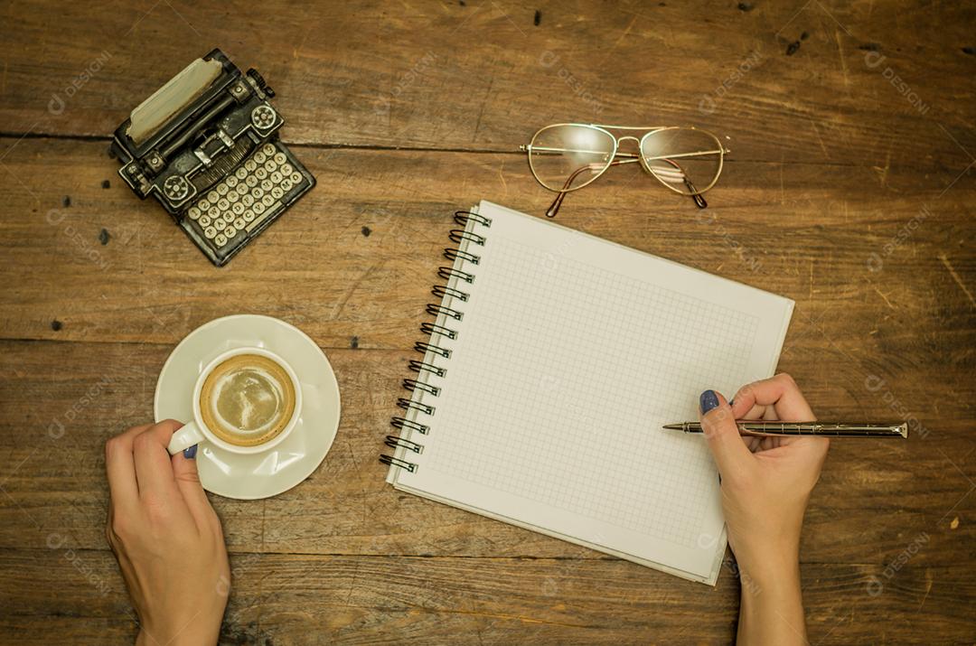 Jovem bebendo café sobre uma xicara de cafe caderno caneta