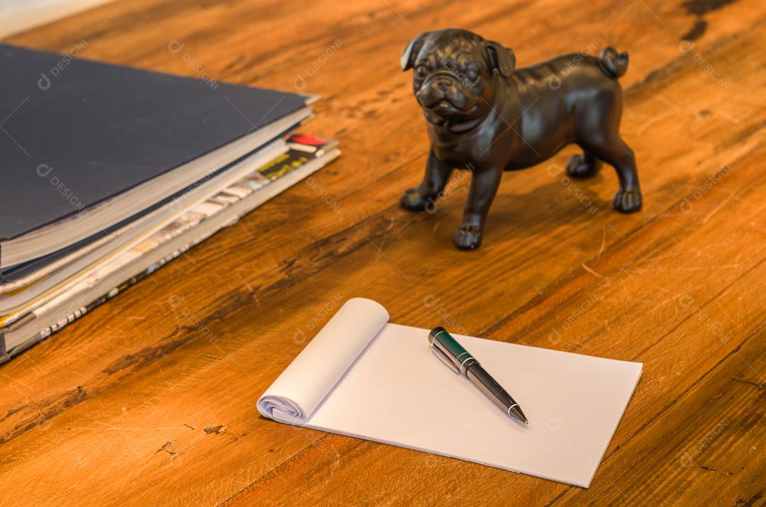 Papel caderno caneta encima de uma mesa de madeira
