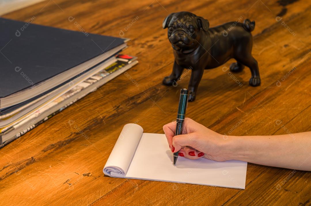 Papel caderno caneta encima de uma mesa de madeira