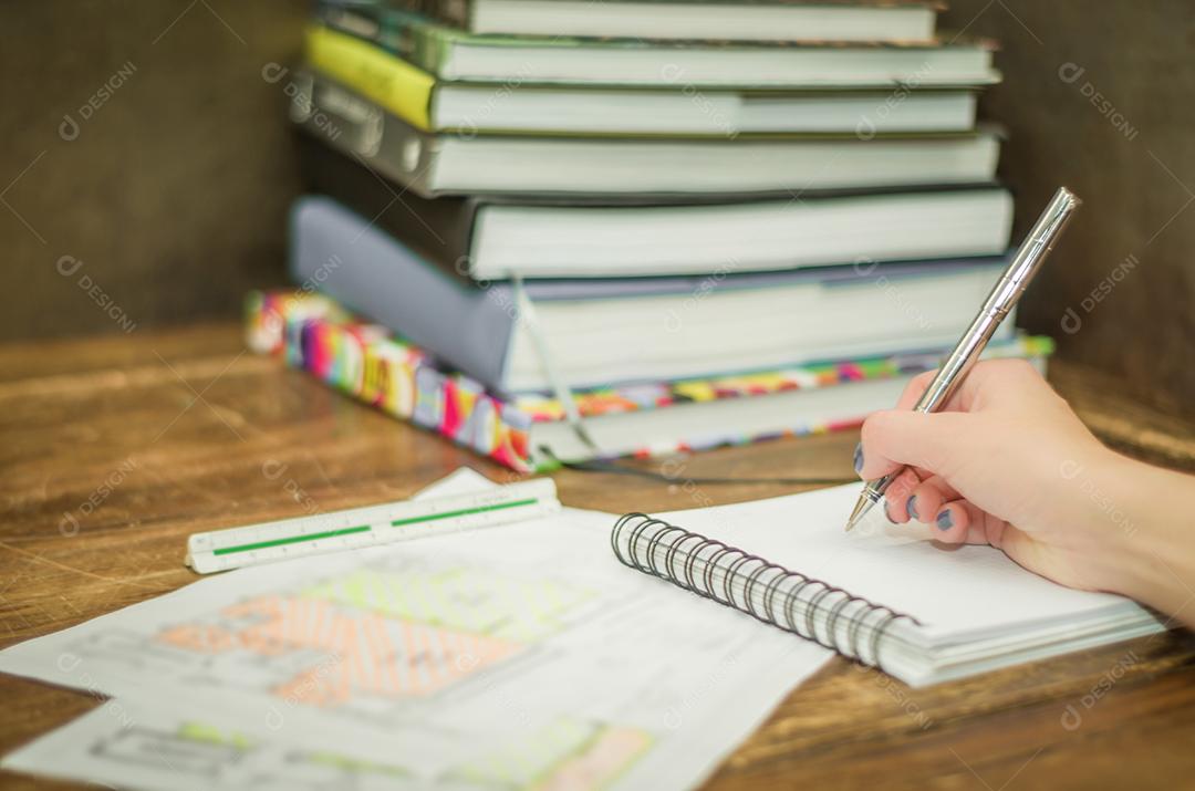 Pessoa escrevendo papel caneta livros